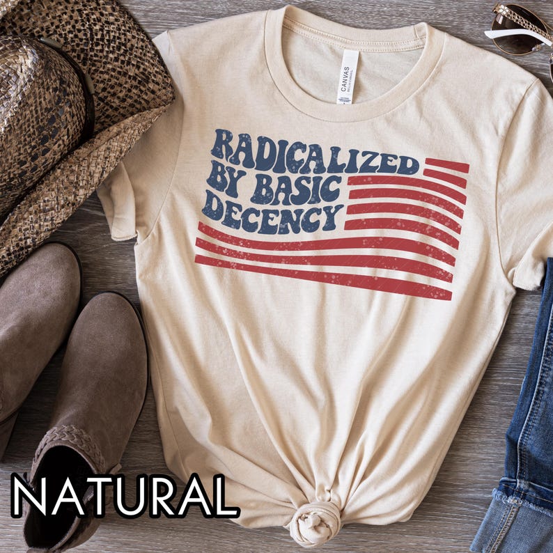 Pu&ograve; includere: Una maglietta color crema con la scritta "RADICALIZED BY BASIC DECENCY" in blu e rosso, disegnata per assomigliare a una bandiera. La maglietta &egrave; realizzata in materiale morbido ed &egrave; adatta per un abbigliamento casual.