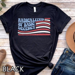 Pu&ograve; includere: T-shirt nera con la scritta "RADICALIZED BY BASIC DECENCY" in blu e rosso, con un disegno a bandiera rossa, bianca e blu. La parola "BLACK" &egrave; stampata in basso sulla maglietta.