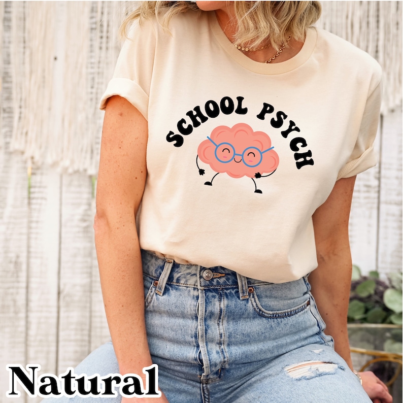 May include: A white t-shirt with a black graphic of a cartoon brain wearing glasses and the text "SCHOOL PSYCH" in a retro font.