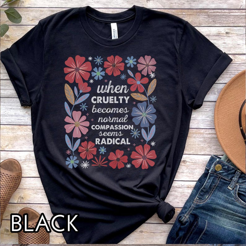 May include: Black t-shirt with a floral design and the text "when cruelty becomes normal compassion seems radical." The design includes red, pink, and blue flowers. The word "BLACK" is printed at the bottom of the shirt.