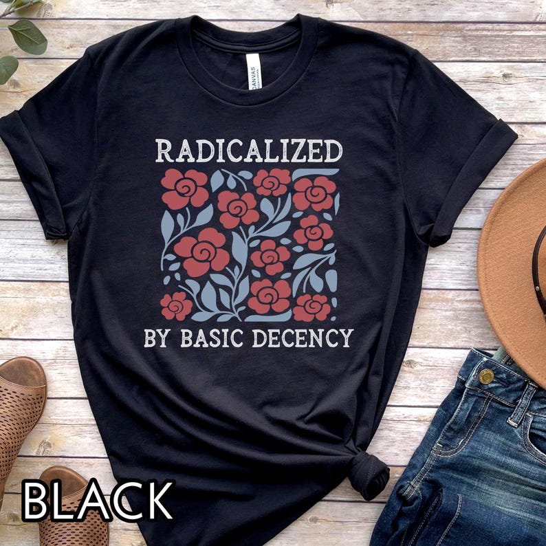May include: Black t-shirt with the text "RADICALIZED BY BASIC DECENCY" in white. The shirt features a floral design in red and blue. The word "BLACK" is printed at the bottom of the shirt.