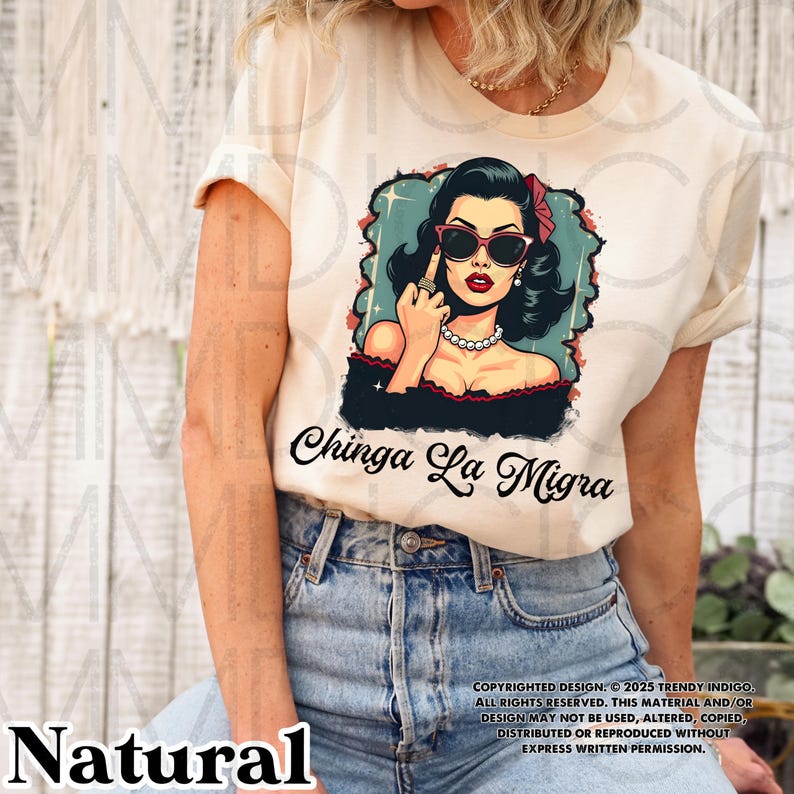 May include: A white t-shirt with a graphic of a woman wearing sunglasses and a red bow in her hair. The woman is giving the middle finger and the text "Chinga La Migra" is printed below the graphic.