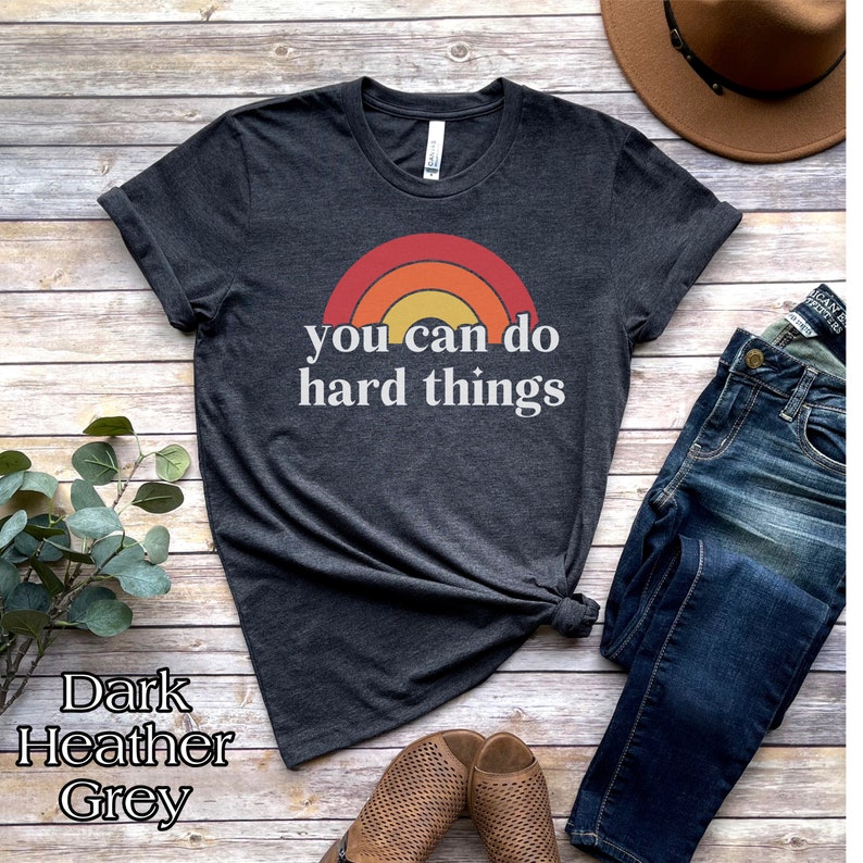 May include: Dark heather grey t-shirt with a rainbow graphic and the text "you can do hard things".