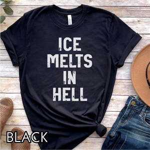 May include: Black t-shirt with the text "ICE MELTS IN HELL" in white block letters. The word "BLACK" is printed at the bottom of the shirt. The shirt is styled with rolled-up sleeves and a knot at the waist.