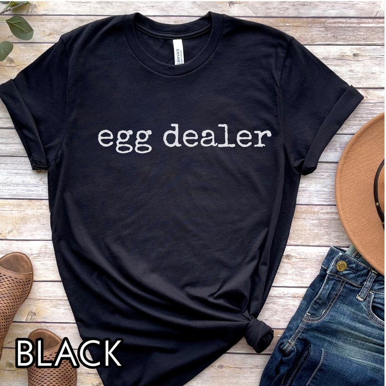May include: Black t-shirt with the text "egg dealer" printed in white.