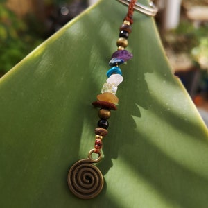 May include: A brown leather keychain with a spiral charm and a string of colorful beads, including turquoise, amethyst, and gold.