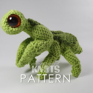 May include: Green crocheted amigurumi toy resembling a mantis with large brown eyes. The toy is standing on a white surface. The text "complicated knots pattern" is visible below the toy.