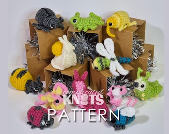 May include: A collection of crocheted amigurumi animal toys, including a bee, ladybug, snail, dragonfly, caterpillar, and a few others. The toys are displayed in small cardboard boxes with silver tinsel.