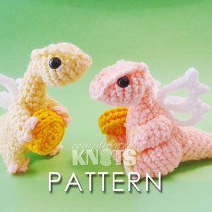 May include: Two crocheted winged dragons, one yellow and one pink, holding small yellow crocheted balls. The dragons are sitting on a green background with the text "complicated knots pattern" below them.