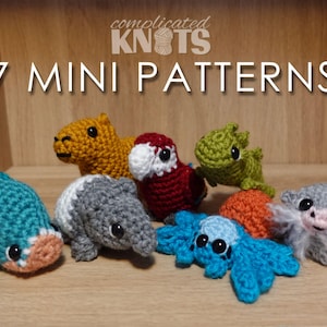 Puede incluir: Siete patrones de animales amigurumi de crochet, incluyendo una ballena azul, un armadillo gris, un capibara amarillo, un loro rojo, un lagarto verde, un cangrejo azul y turquesa y un oso gris y blanco. Los patrones se muestran en un estante de madera con el texto "7 MINI PATTERNS" y "complicated KNOTS" encima.
