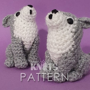 Op de afbeelding: Twee grijze en witte gehaakte wolf knuffels die op een paarse ondergrond zitten. De knuffels hebben zwarte ogen en neuzen.