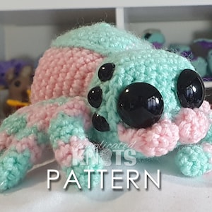 May include: A crocheted amigurumi spider toy with pink and green stripes. The spider has large black eyes and is sitting on a white surface. The text "Complicated Knots Pattern" is visible in the image.
