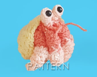 May include: A crocheted hermit crab toy with a pink body and yellow shell. The crab has black eyes and a long, thin tail.
