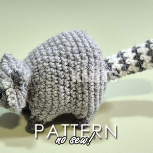 May include: A crocheted raccoon amigurumi toy with a gray and white striped tail. The toy is made with a no-sew technique.  PATTERN no sew!