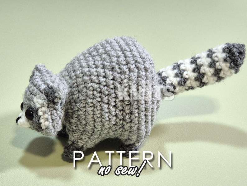 May include: A crocheted raccoon amigurumi toy with a gray and white striped tail. The toy is made with a no-sew technique.  PATTERN no sew!