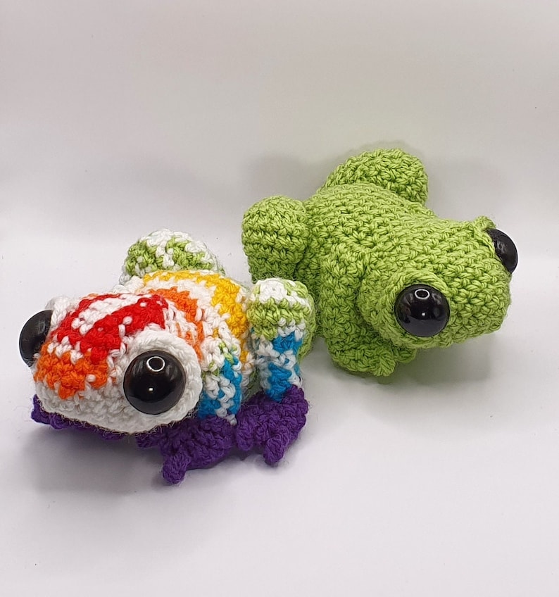 May include: Two crocheted frog plushies. One is green and the other is rainbow colored.