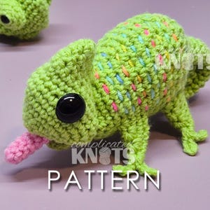 May include: Crocheted chameleon toy in shades of green with colourful speckles. The chameleon has a pink tongue extended and large black eyes. The word "PATTERN" is displayed in white text at the bottom of the image.