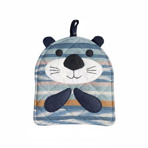 May include: A blue and white striped oven mitt shaped like an otter. The mitt features a quilted pattern, black eyes, a black nose, and dark blue ears and paws. A small loop is attached for hanging.