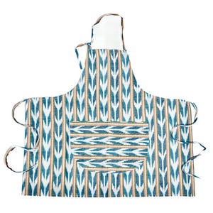 May include: An apron with a blue, white, and tan geometric pattern. The apron has a pocket and ties at the waist and neck. The apron is made of fabric.