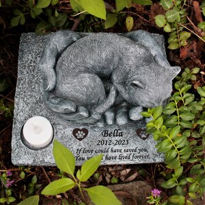 May include: A gray stone memorial for a pet with a sleeping cat sculpture. The inscription reads "Bella 2012-2023 If love could have saved you, You w I have lived forever."
