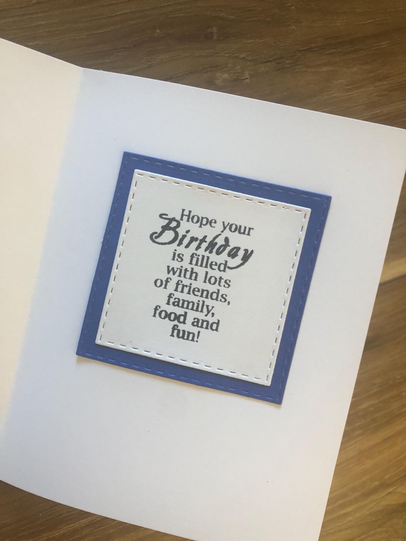 May include: A white card with a blue border and a message that reads "Hope your Birthday is filled with lots of friends, family, food and fun!"