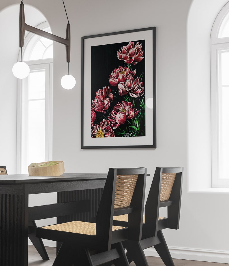 K&ouml;nnte beinhalten: Ein gerahmtes Gem&auml;lde von rosa Pfingstrosen auf schwarzem Hintergrund. Das Gem&auml;lde h&auml;ngt an einer wei&szlig;en Wand in einem modernen Esszimmer mit einem schwarzen Tisch und zwei St&uuml;hlen.