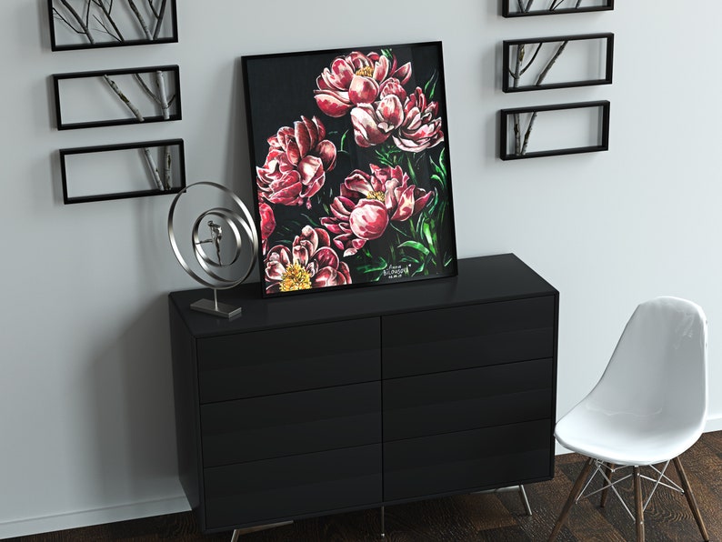 K&ouml;nnte beinhalten: Ein schwarzer gerahmter Druck eines Gem&auml;ldes mit rosa Pfingstrosen auf dunklem Hintergrund. Der Druck h&auml;ngt an einer wei&szlig;en Wand &uuml;ber einer schwarzen Kommode mit sechs Schubladen. Eine silberne Metallskulptur steht auf der Kommode links neben dem Druck.