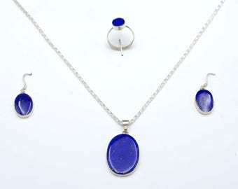 May include: A jewellery set comprising a silver necklace with a blue oval pendant, matching earrings, and a ring. The set has a bright, polished finish. The blue stones are set in silver.