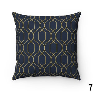 May include: A navy blue throw pillow with a gold geometric pattern. The pattern is made up of repeating shapes that resemble a lattice or trellis.