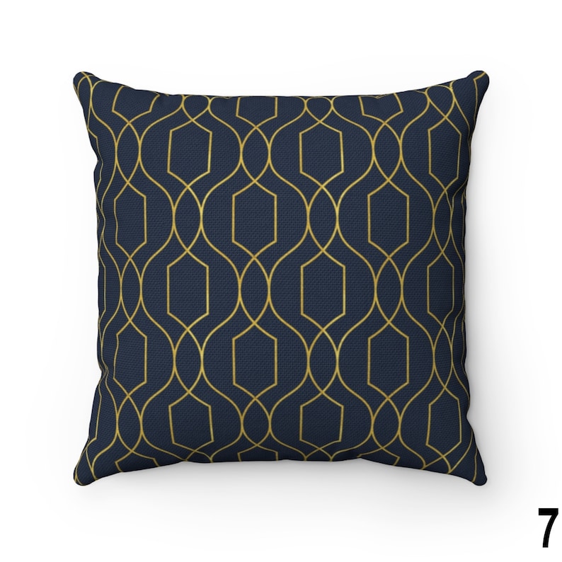 May include: A navy blue throw pillow with a gold geometric pattern. The pattern is made up of repeating shapes that resemble a lattice or trellis.