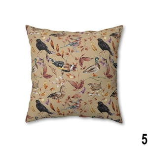 May include: Square throw pillow with a beige background featuring a repeating pattern of various birds, including blackbirds and ducks, amidst autumnal leaves in shades of brown, red, and purple. The pillow has a soft, inviting appearance.