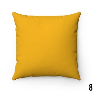 Puede incluir: Una almohada de tiro amarilla s&oacute;lida con una tela lisa y texturizada. La almohada tiene forma cuadrada y tiene un brillo sutil.