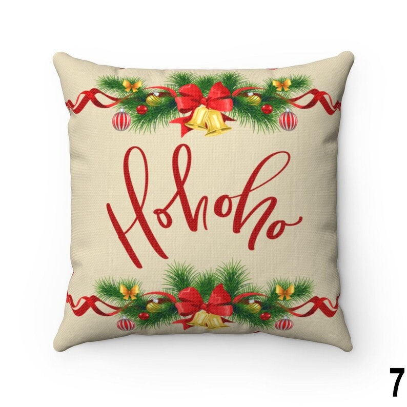 Pu&ograve; includere: Cuscino quadrato con sfondo beige. Il cuscino presenta il testo rosso "Hohoho" in un carattere corsivo. La parte superiore e inferiore del cuscino presentano un motivo a ghirlanda natalizia con fiocchi rossi, campane e ornamenti.
