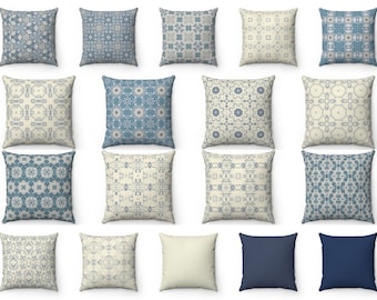 May include: A collection of square throw pillows in various patterns and colors. The pillows feature intricate designs in shades of blue and cream, with some solid navy blue and cream-colored options. The patterns include floral, geometric, and abstract motifs.
