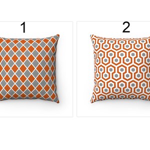 K&ouml;nnte beinhalten: Zwei dekorative Kissen mit geometrischen Mustern. Das Kissen links hat ein Rautenmuster in Orange und Grau. Das Kissen rechts hat ein Wabenmuster in Orange und Grau.