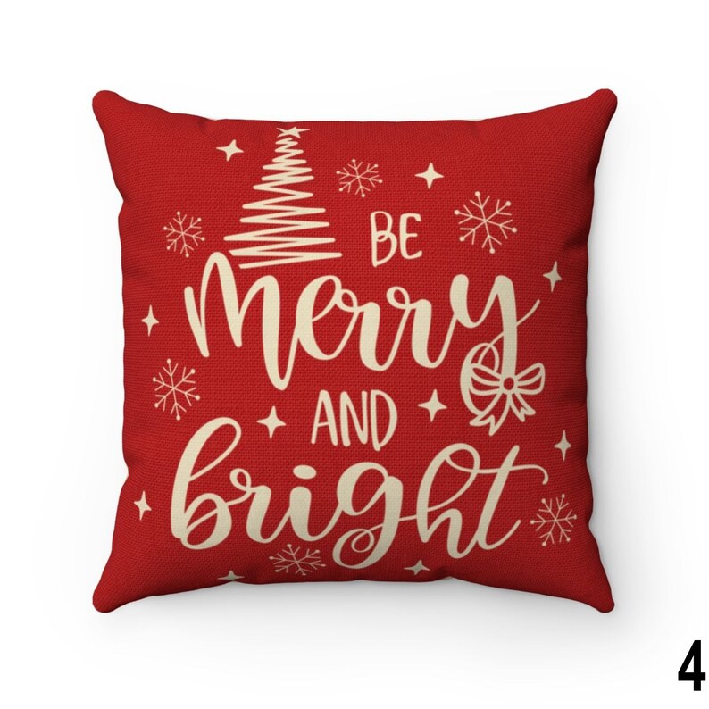 Pu&ograve; includere: Un cuscino quadrato rosso con la scritta "BE merry AND bright" in crema. Il cuscino presenta un albero di Natale, fiocchi di neve e stelle, perfetto per le feste.