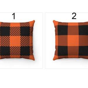 K&ouml;nnte beinhalten: Zwei quadratische Kissen mit einem schwarz-orangenen B&uuml;ffel-Plaid-Muster. Kissen 1 hat diagonale Streifen in den orangefarbenen Quadraten. Kissen 2 hat durchgehend orangefarbene Quadrate. Beide Kissen befinden sich auf wei&szlig;em Hintergrund.