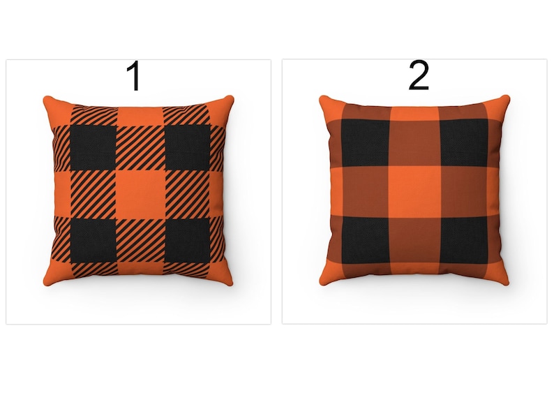 K&ouml;nnte beinhalten: Zwei quadratische Kissen mit einem schwarz-orangenen B&uuml;ffel-Plaid-Muster. Kissen 1 hat diagonale Streifen in den orangefarbenen Quadraten. Kissen 2 hat durchgehend orangefarbene Quadrate. Beide Kissen befinden sich auf wei&szlig;em Hintergrund.