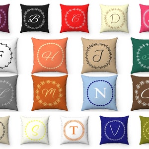 May include: Set of 18 decorative throw pillows with a variety of colors and patterns. Each pillow features a different letter of the alphabet in a white wreath. The pillows are arranged in three rows of six.