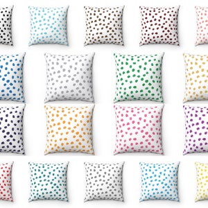 May include: A collection of throw pillows with a white background and a pattern of irregularly shaped dots. The dots are in various colors, including black, blue, brown, burgundy, pink, gray, green, yellow, orange, and purple. The pillows are square.