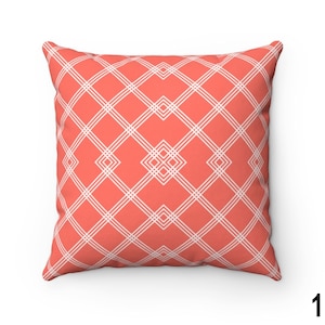 May include: A coral coloured throw pillow with a white geometric pattern. The pattern is a series of intersecting lines that create a diamond shape.
