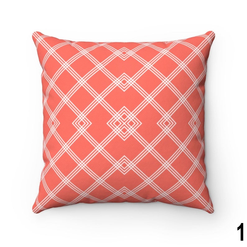 May include: A coral coloured throw pillow with a white geometric pattern. The pattern is a series of intersecting lines that create a diamond shape.