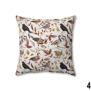 May include: Square throw pillow with a repeating pattern of various birds and autumn leaves in shades of brown, orange, and purple on a white background. The pillow has a soft, inviting appearance.