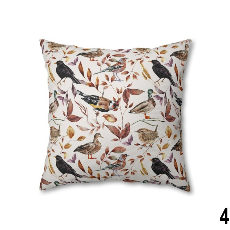 May include: Square throw pillow with a repeating pattern of various birds and autumn leaves in shades of brown, orange, and purple on a white background. The pillow has a soft, inviting appearance.
