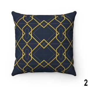 May include: A navy blue throw pillow with a gold geometric pattern. The pattern is made up of overlapping squares and rectangles.