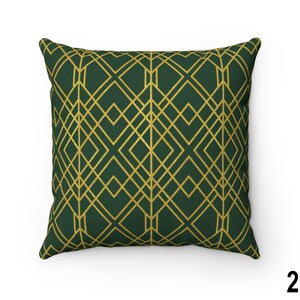 Puede incluir: Coj&iacute;n cuadrado con un patr&oacute;n geom&eacute;trico dorado sobre un fondo verde oscuro. El dise&ntilde;o presenta l&iacute;neas que se cruzan formando rombos. La almohada es un art&iacute;culo decorativo para el hogar.