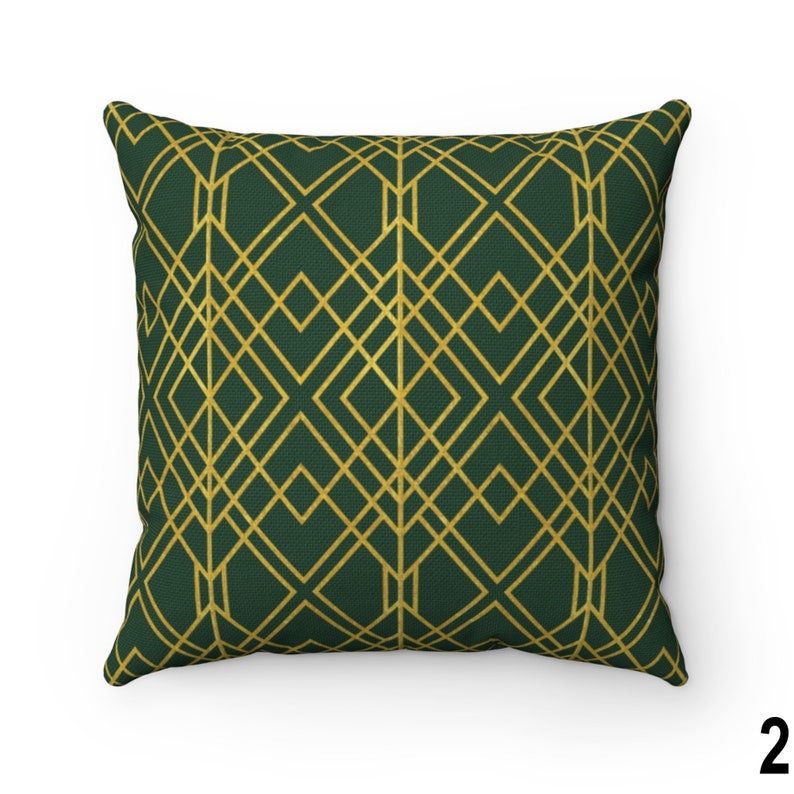 Puede incluir: Coj&iacute;n cuadrado con un patr&oacute;n geom&eacute;trico dorado sobre un fondo verde oscuro. El dise&ntilde;o presenta l&iacute;neas que se cruzan formando rombos. La almohada es un art&iacute;culo decorativo para el hogar.