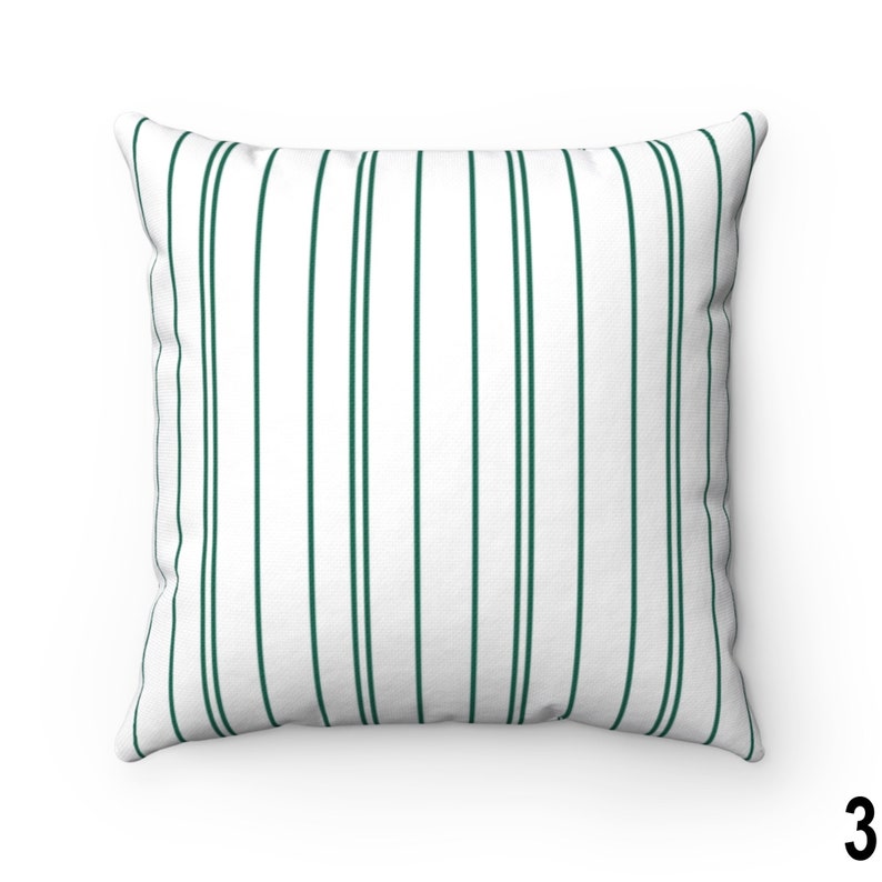 May include: A white throw pillow with dark green vertical stripes. The pillow is a square shape and has a white background.