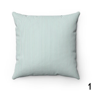 May include: A white pillow with thin, dark green vertical stripes. The pillow is square and has a soft, plush texture.