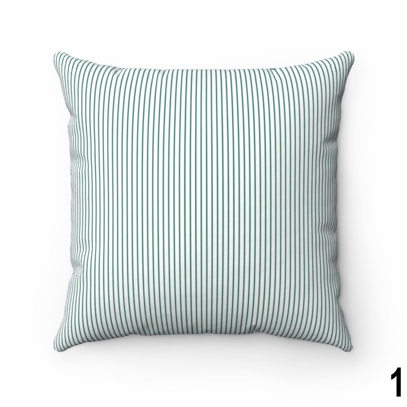 May include: A white pillow with thin, dark green vertical stripes. The pillow is square and has a soft, plush texture.